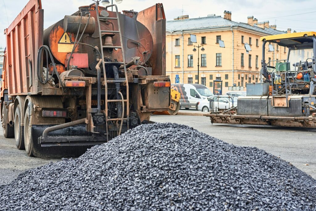 Hot asphalt and trick with a bitumen in city. Road construction